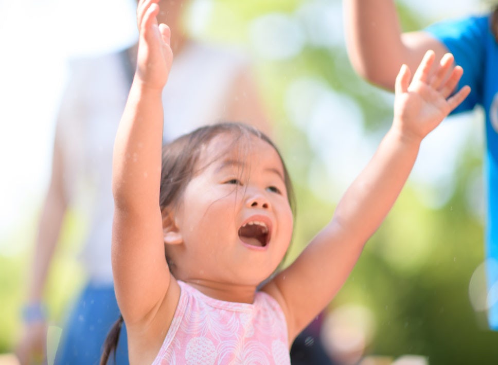Girl with hands raised playing and smiling at the Zoo